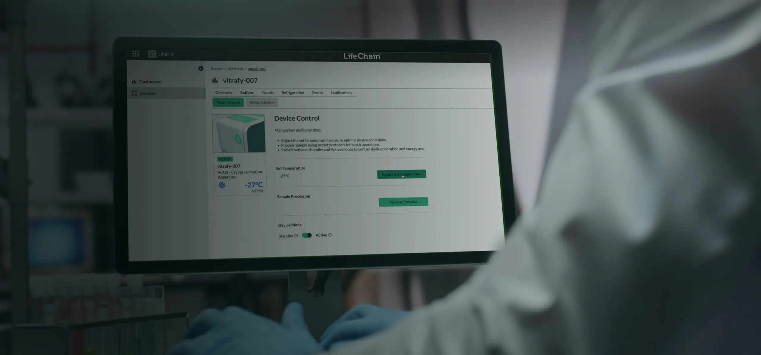 A gowned operator at a workstation running LifeChain device control in a cryogenics lab.